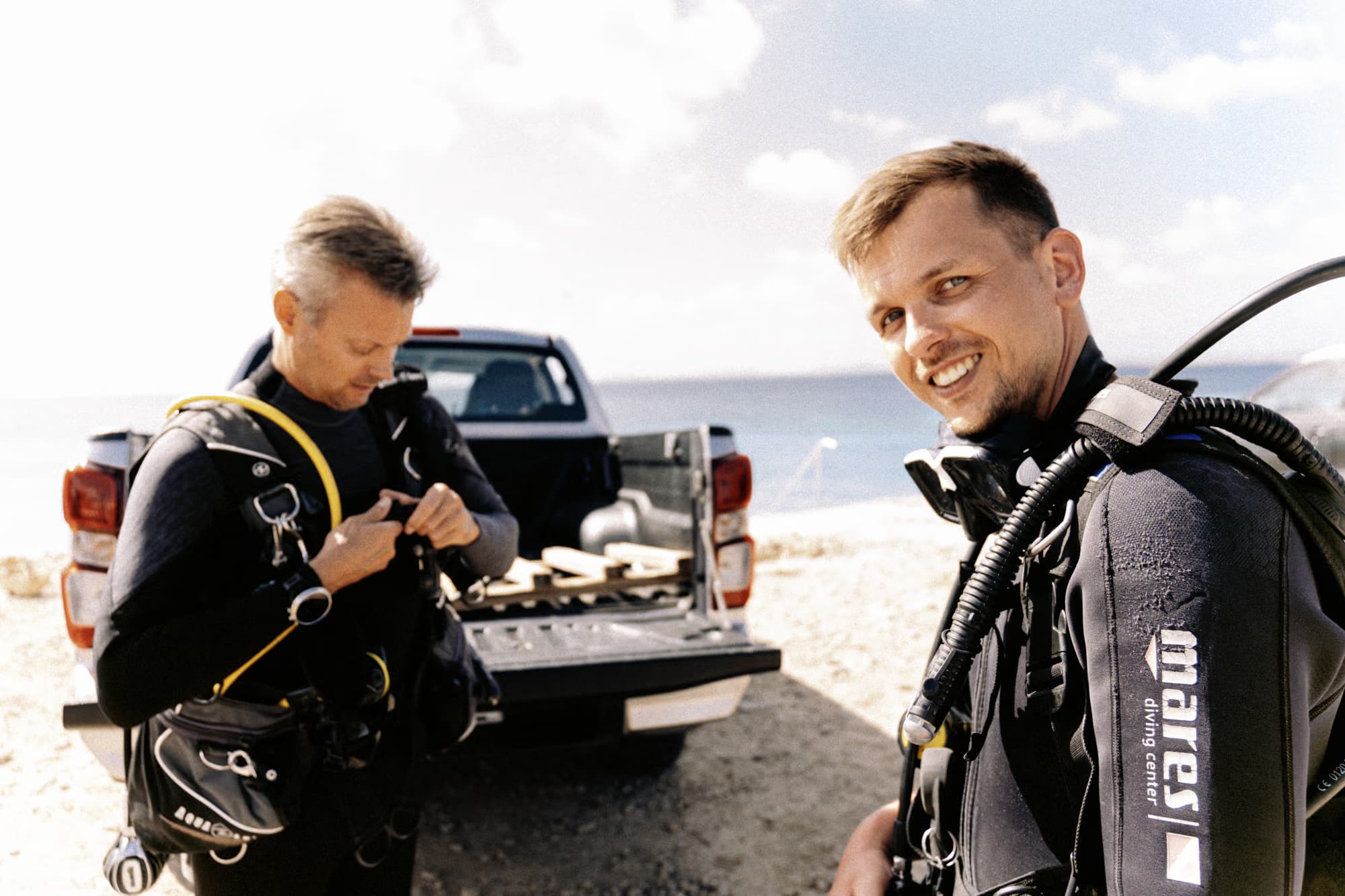 Twee duikers maken zich klaar op het strand