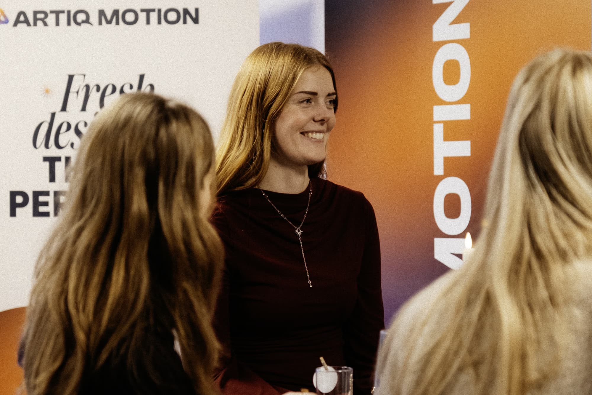 Lachende vrouw bij Artiq Motion-banner tijdens netwerkevenement