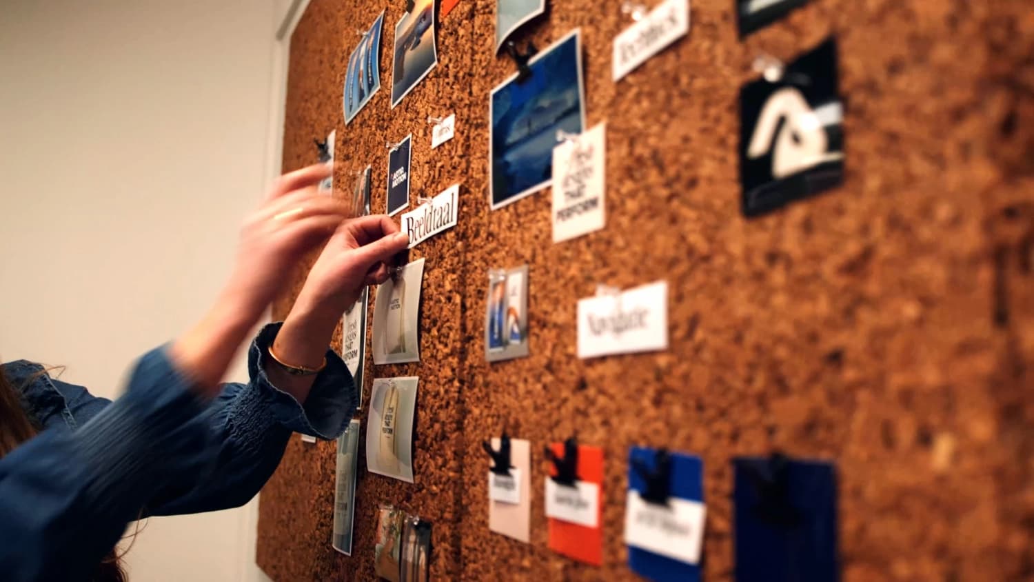 Handen die kaartjes vastprikken op een kurken moodboard